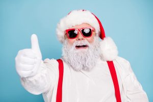 Close up photo of funny funky fat overweight santa claus have modern hipster eyeglasses show thumb up recommend winter season sales, wear red suspenders overalls isolated over blue color background